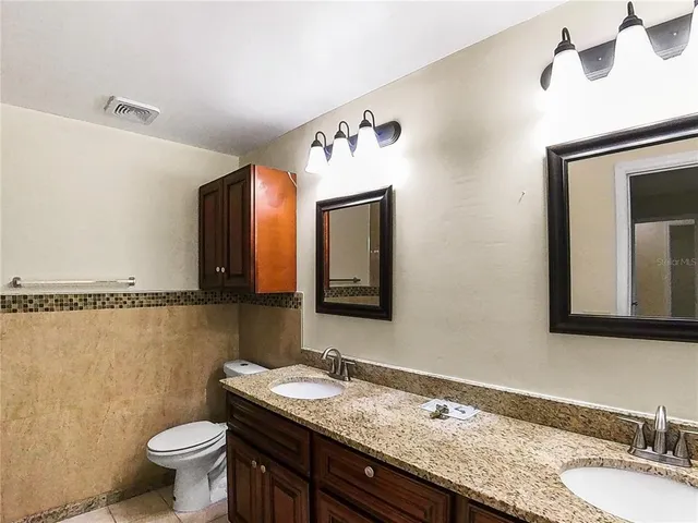 a bathroom with a granite countertop sink a mirror and a toilet