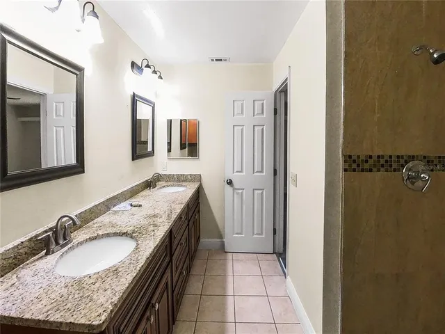 a bathroom with a granite countertop double vanity sink and mirror