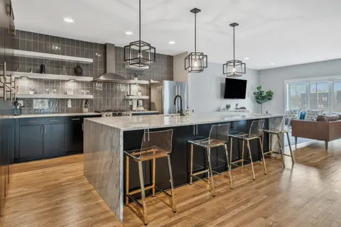 a kitchen with stainless steel appliances kitchen island granite countertop a table chairs in it and wooden floors