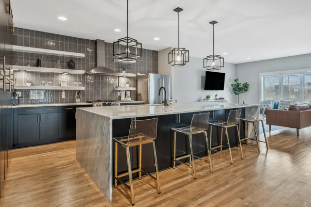 a kitchen with stainless steel appliances kitchen island granite countertop a table chairs in it and wooden floors