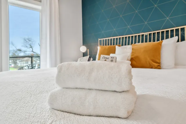 a large white bed sitting in a bedroom next to a window