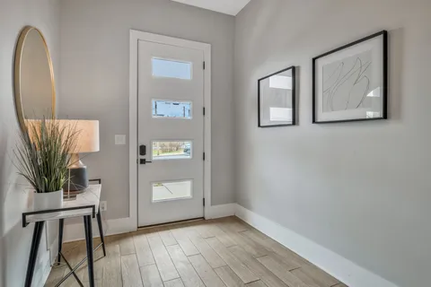 a view of a hallway with wooden floor and a bathroom