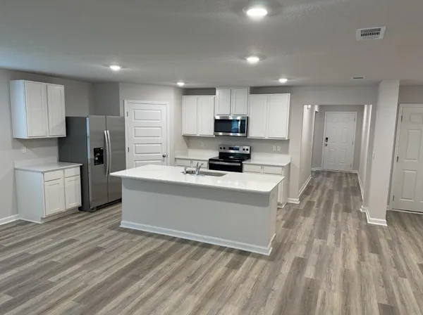a view of kitchen with microwave a stove and a refrigerator