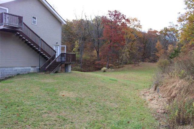 a view of a backyard with large trees and a small barn