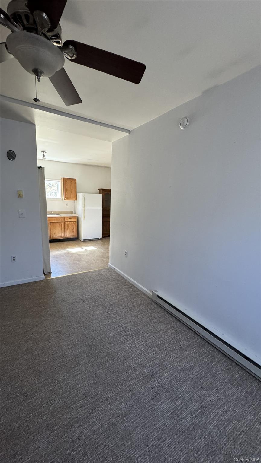 400 Round Lake Road Rhinebeck, NY 12572 - Photo 31 of 34 Unfurnished living room featuring baseboard heating, carpet flooring, and ceiling fan