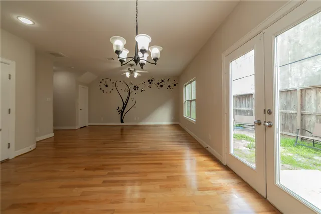 a view of a room with wooden floor chandeliers and kitchen view