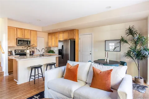 a living room with stainless steel appliances kitchen island granite countertop wooden floor a couch and a window