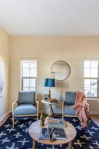 a living room with furniture a rug a lamp and a window