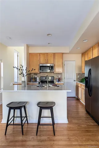 a kitchen with stainless steel appliances granite countertop a table chairs and a refrigerator
