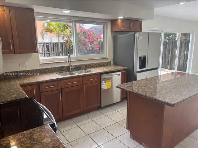 a kitchen with stainless steel appliances granite countertop a sink and a refrigerator