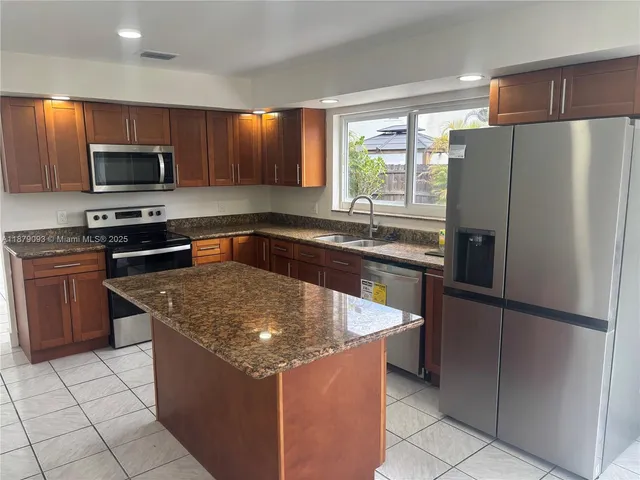 a kitchen with stainless steel appliances granite countertop a refrigerator a sink a stove a microwave and cabinets