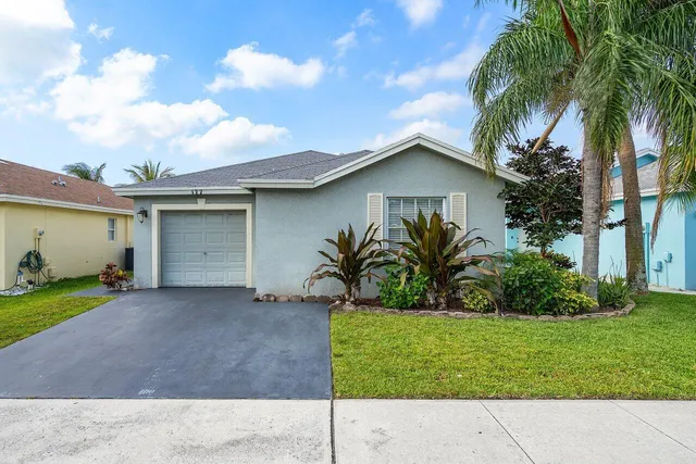 a white house with a small yard and a large parking space