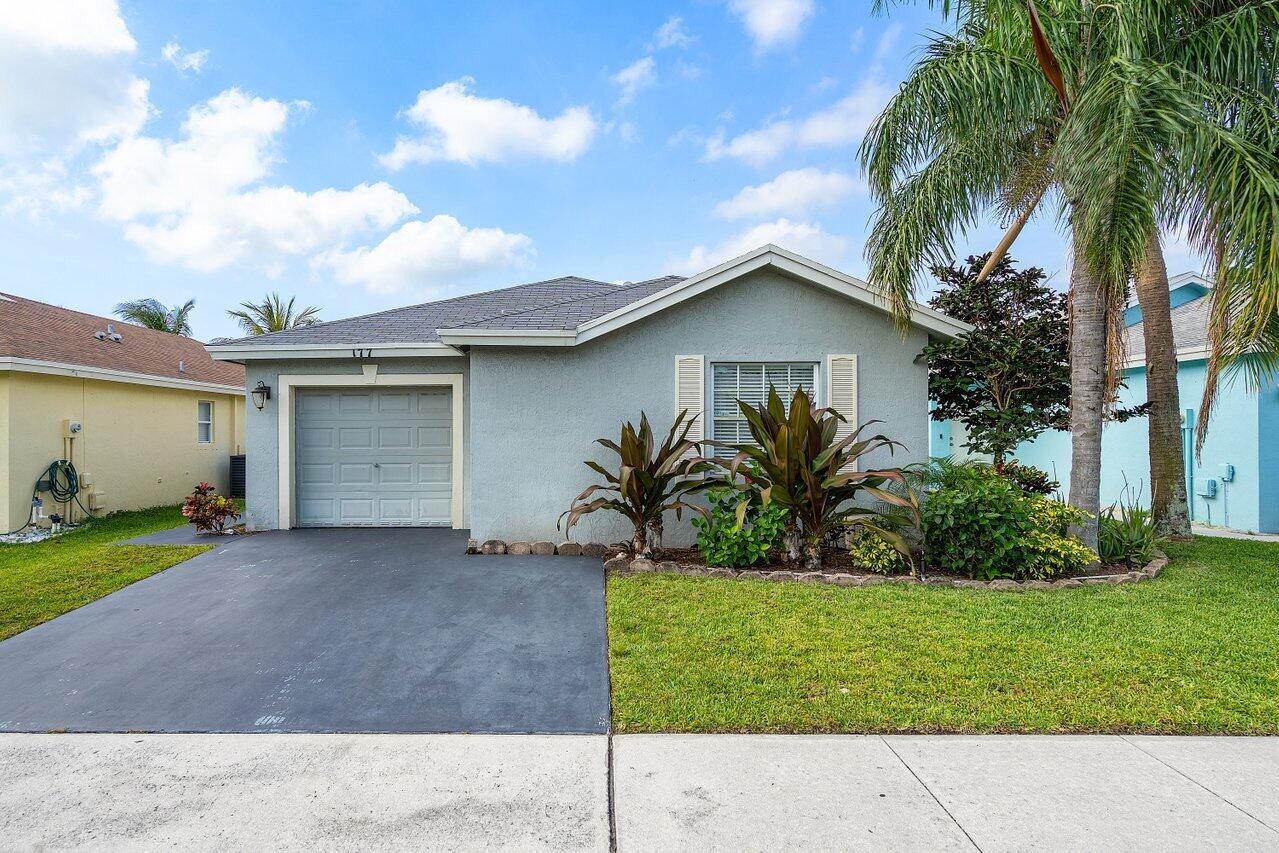 a white house with a small yard and a large parking space