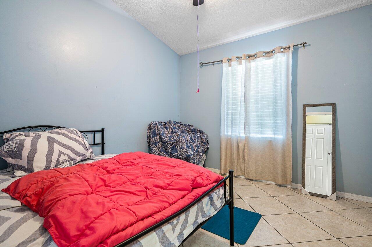 177 Heming Way Boynton Beach, FL 33426 - Photo 12 of 22 a bed sitting in a bedroom next to a window and a chandelier