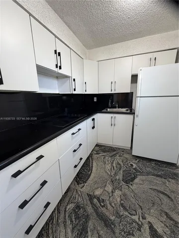 a kitchen with granite countertop white cabinets and black appliances