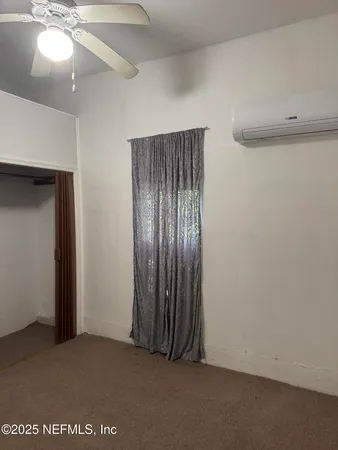 an empty room with a ceiling fan and closet area