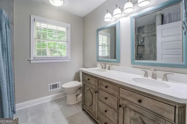 a bathroom with a double vanity sink a toilet and a mirror