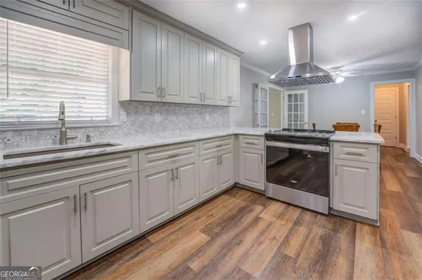 a kitchen with stainless steel appliances granite countertop a sink cabinets a stove and a window