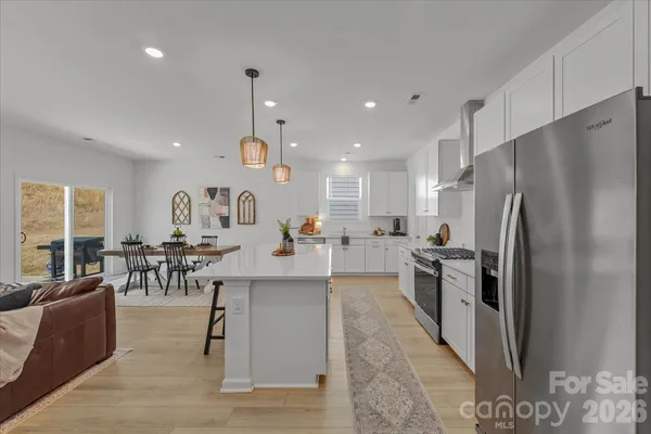 a kitchen with stainless steel appliances kitchen island granite countertop a refrigerator a stove a sink a dining table and chairs with wooden floor