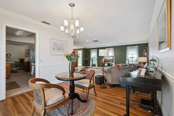 a view of a dining room with furniture a chandelier and wooden floor