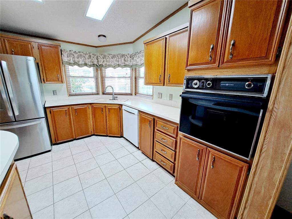116 Maple Leaf Drive Palm Harbor, FL 34684 - Photo 8 of 38 a kitchen with stainless steel appliances granite countertop a refrigerator a sink dishwasher and wooden cabinets