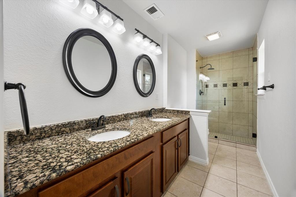 925 Lake North Road Rowlett, TX 75089 - Photo 25 of 37 Double vanity with granite countertops, wood-finish cabinetry, and dual oval mirrors