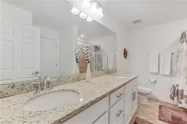 a bathroom with a granite countertop double vanity sink and a mirror