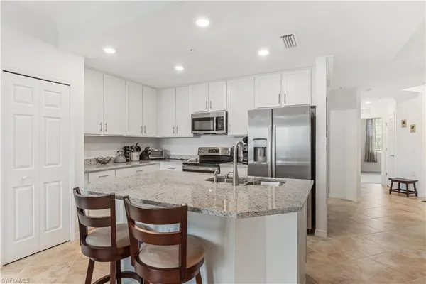 a kitchen with a refrigerator a stove a sink and chairs