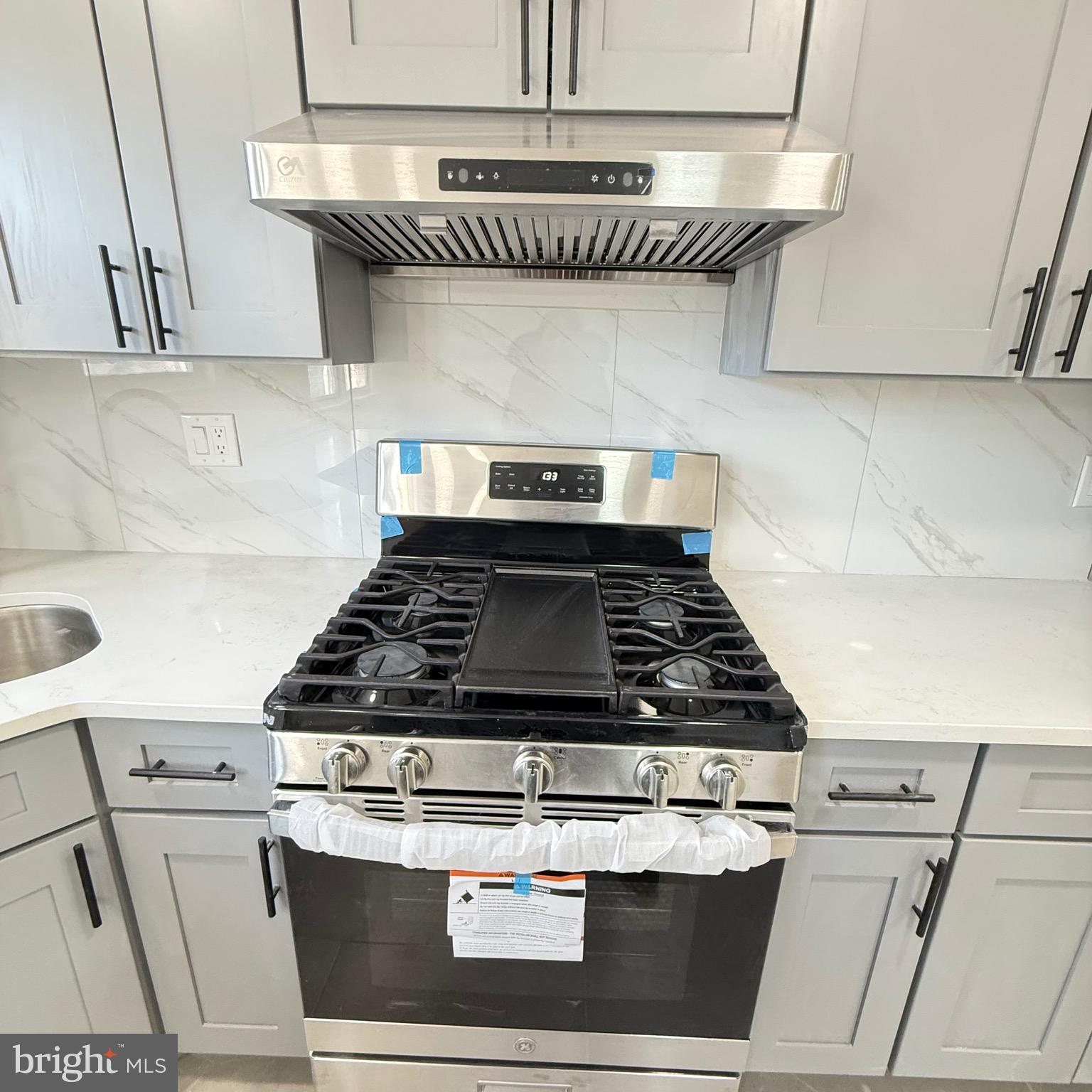 7219 Large Street Philadelphia, PA 19149 - Photo 18 of 20 a stove sitting inside of a kitchen with stainless steel appliances wooden floor and cabinets