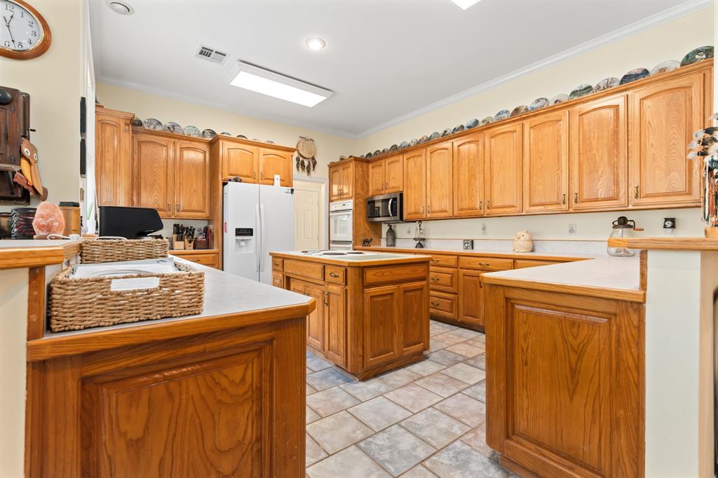 1264 Overlook Drive Whitney, TX 76692 - Photo 27 of 39 a kitchen with stainless steel appliances granite countertop a stove top oven a sink dishwasher and a refrigerator with wooden cabinets