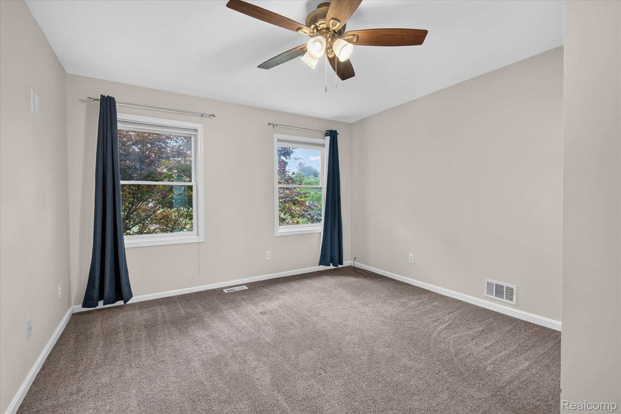 8114 Chilson Road Pinckney, MI 48169 - Photo 11 of 32 Carpeted room featuring two windows with white trim, a ceiling fan with light fixture, and light-toned walls