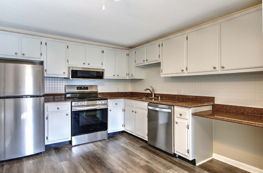 91 Pleasant Street, Unit A6 Medfield, MA 02052 - Photo 11 of 29 a kitchen with cabinets stainless steel appliances and wooden floor