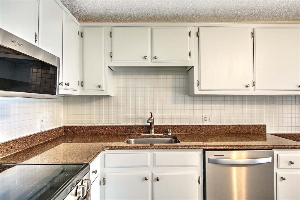91 Pleasant Street, Unit A6 Medfield, MA 02052 - Photo 12 of 29 a kitchen with stainless steel appliances granite countertop a sink a stove and microwave