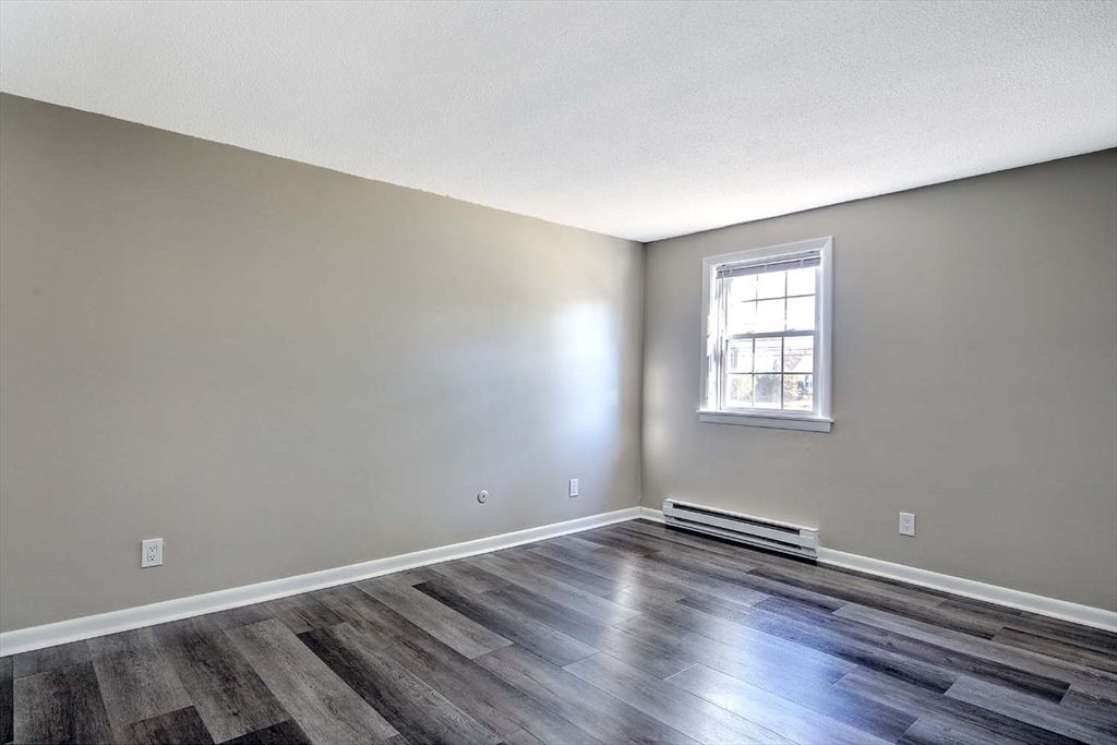 91 Pleasant Street, Unit A6 Medfield, MA 02052 - Photo 14 of 29 an empty room with wooden floor and windows