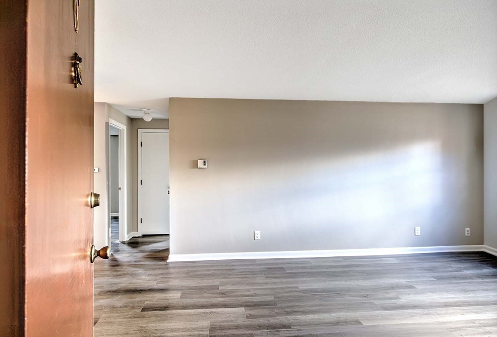 91 Pleasant Street, Unit A6 Medfield, MA 02052 - Photo 4 of 29 an empty room with wooden floor and windows