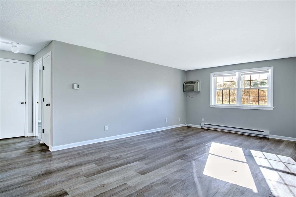 91 Pleasant Street, Unit A6 Medfield, MA 02052 - Photo 5 of 29 an empty room with wooden floor and windows