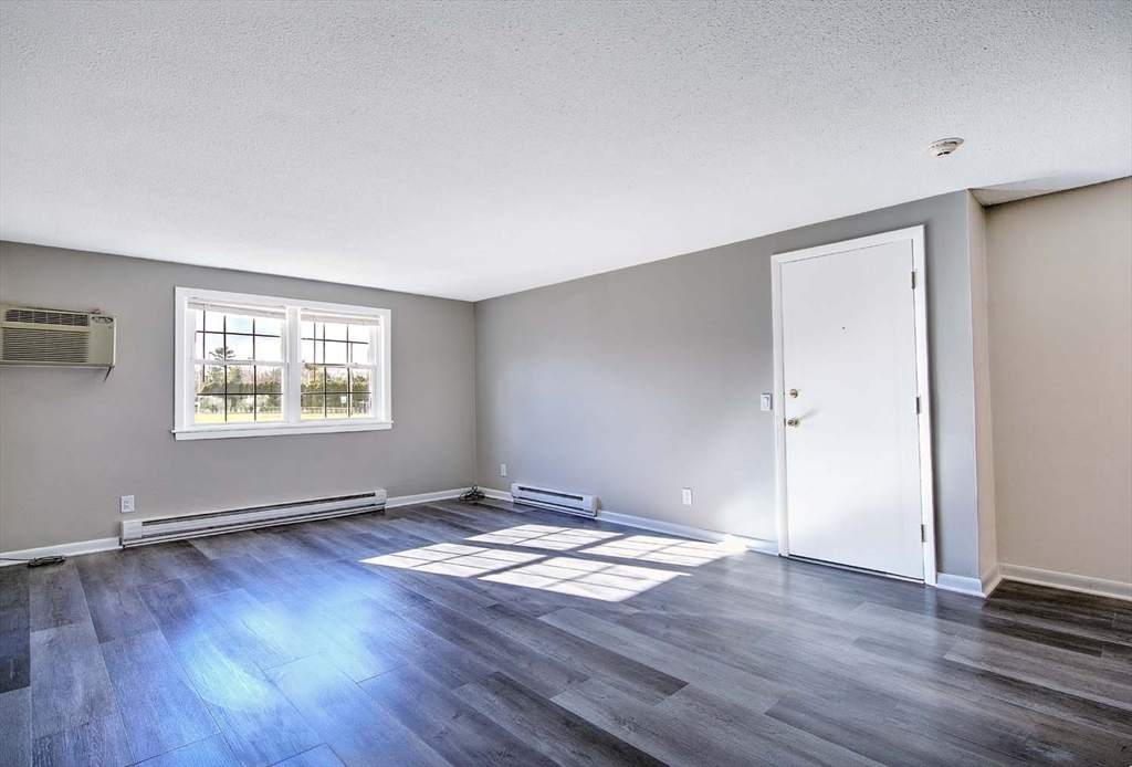 91 Pleasant Street, Unit A6 Medfield, MA 02052 - Photo 6 of 29 an empty room with wooden floor and windows