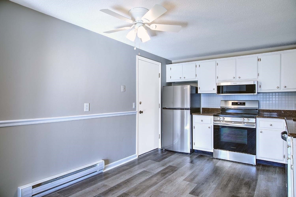 91 Pleasant Street, Unit A6 Medfield, MA 02052 - Photo 9 of 29 a kitchen with stainless steel appliances white cabinets and wooden floor