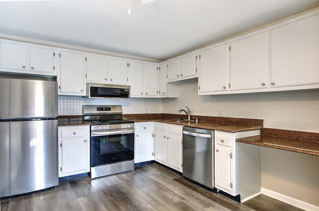 91 Pleasant Street, Unit A6 Medfield, MA 02052 - Photo 10 of 29 a kitchen with cabinets stainless steel appliances and wooden floor