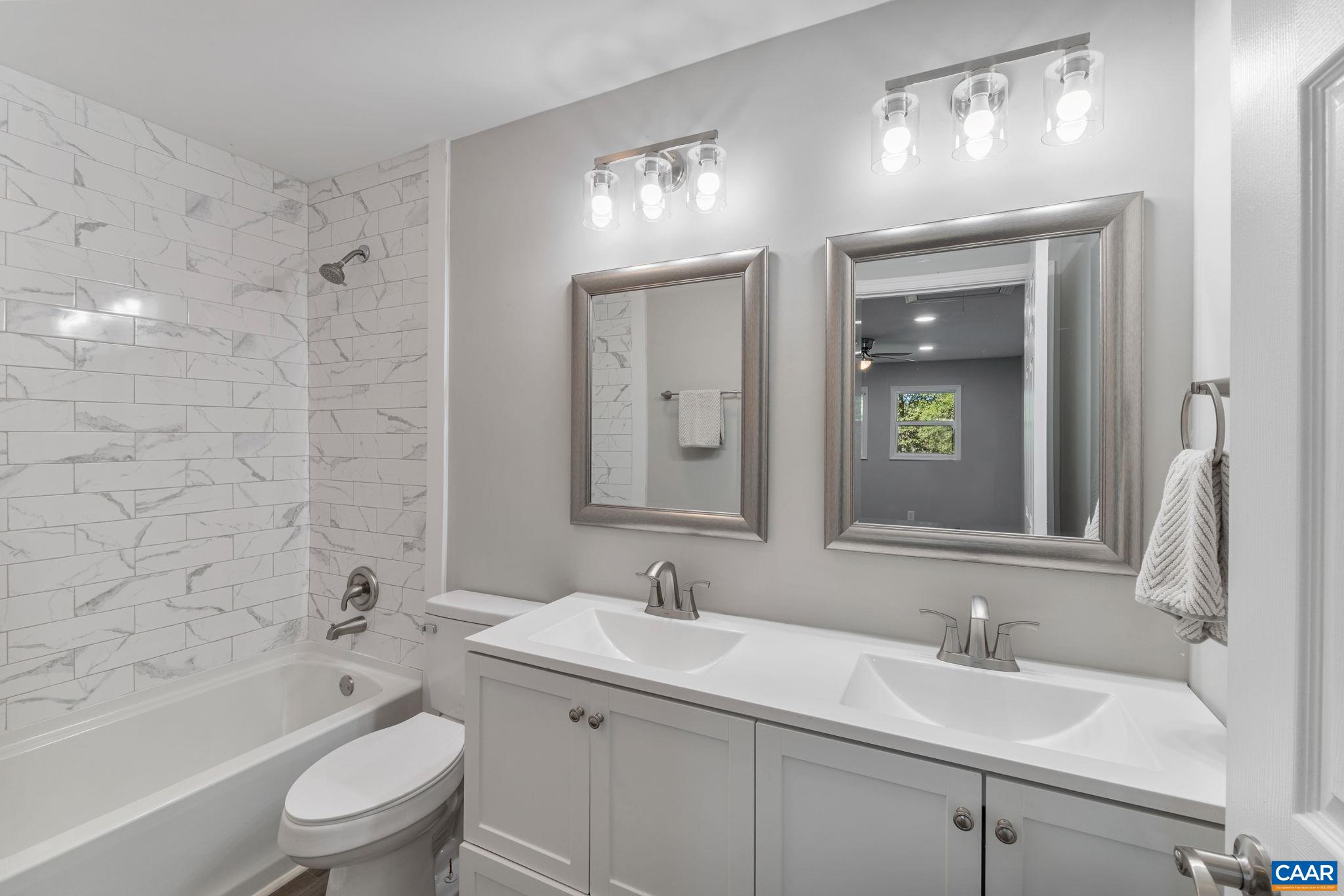 612 Oneals Road Pratts, VA 22731 - Photo 25 of 68 a bathroom with a granite countertop sink toilet a large mirror a bathtub and shower