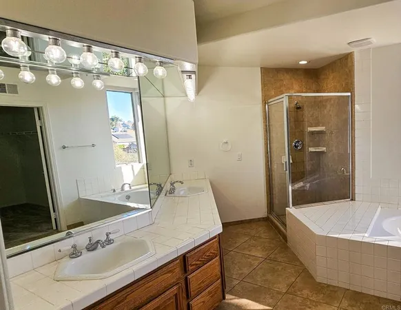 a spacious bathroom with a granite countertop tub sink shower and mirror