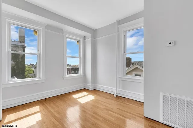 an empty room with wooden floor and windows