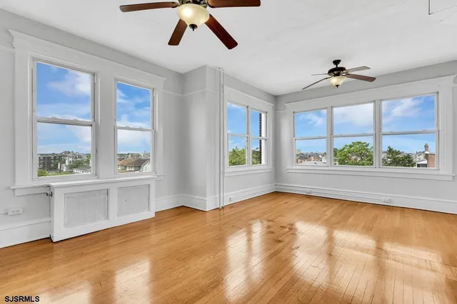 a view of an empty room with a window and kitchen view