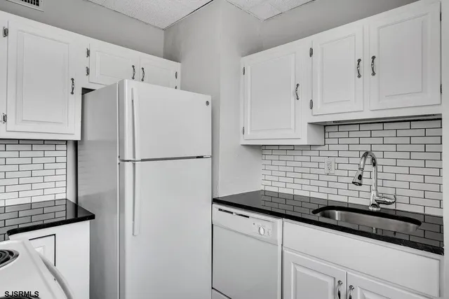 a kitchen with stainless steel appliances a refrigerator a sink a stove and white cabinets