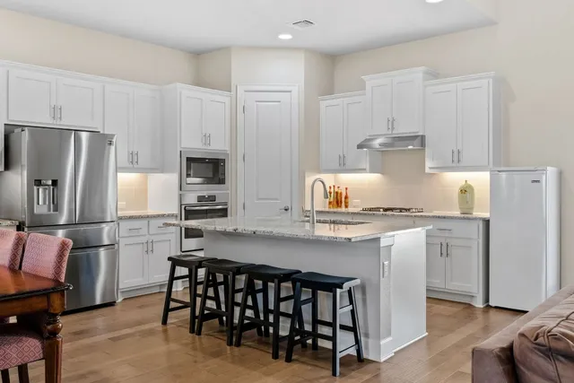a kitchen with refrigerator a stove a sink and chairs