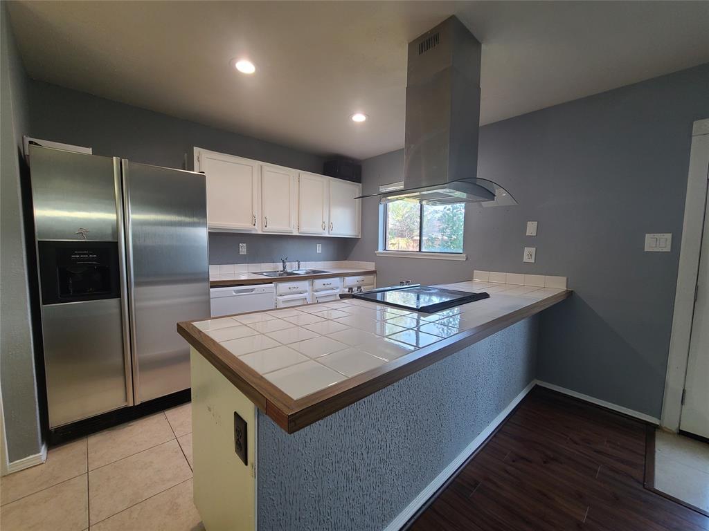 5644 Perrin Street The Colony, TX 75056 - Photo 4 of 16 Kitchen with cooktop, white cabinetry, island exhaust hood, stainless steel fridge, and light hardwood / wood-style flooring