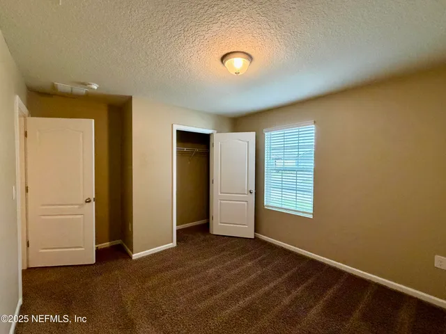 a view of an empty room with a window and a kitchen