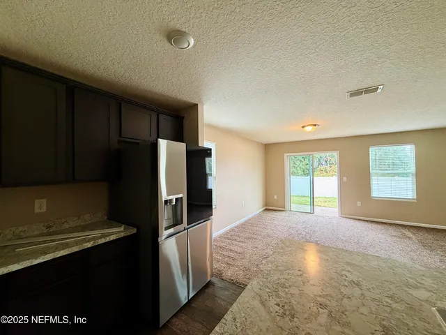 a view of a kitchen with refrigerator and window