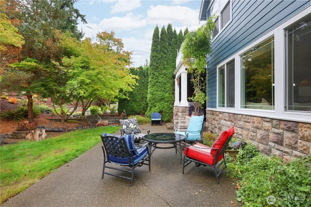 a view of a patio with table and chairs potted plants and a large tree