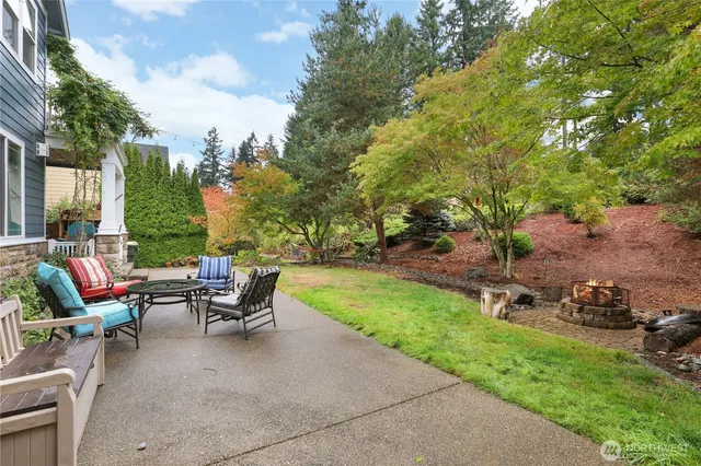 a view of a backyard with table and chairs plants and large trees
